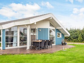 A modern house with a covered patio, large windows, and a dining area with outdoor furniture. - 4 Star Holiday Home in Hejls (Hejls)