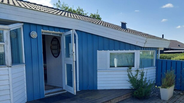 A blue mobile home with a wooden deck, a front door, and a window. - 4 Star Holiday Home in Hejls (Hejls)