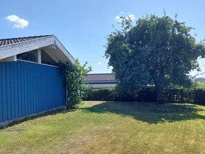 A blue building with a sloped roof, a grassy yard, and a large tree. - 4 Star Holiday Home in Hejls (Hejls)