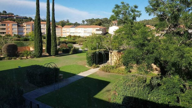 Zona residencial con césped cuidado, altos cipreses y un camino que lleva a una entrada con portón.