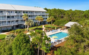Ein Hotel mit Schwimmbad, mehreren Balkonen und üppiger Bepflanzung.