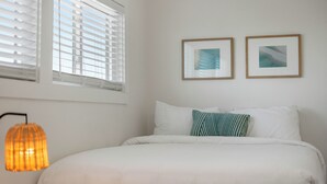A bedroom with a bed, two pillows, a wall-mounted picture, and a window with blinds. - Salt Haus 30A: Pet Friendly Gulf View Loft (Santa Rosa Beach)
