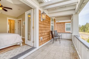 Ein Schlafzimmer mit einem Bett, einer Tür, die auf einen Balkon führt, und einem Stuhl auf dem Balkon.