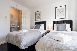 Ein Hotelzimmer mit zwei Betten, einem Badezimmer und Bildern an den Wänden.