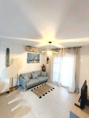 Ein Wohnzimmer mit einer Couch, einem Couchtisch, einem Fernseher und einem Deckenventilator.