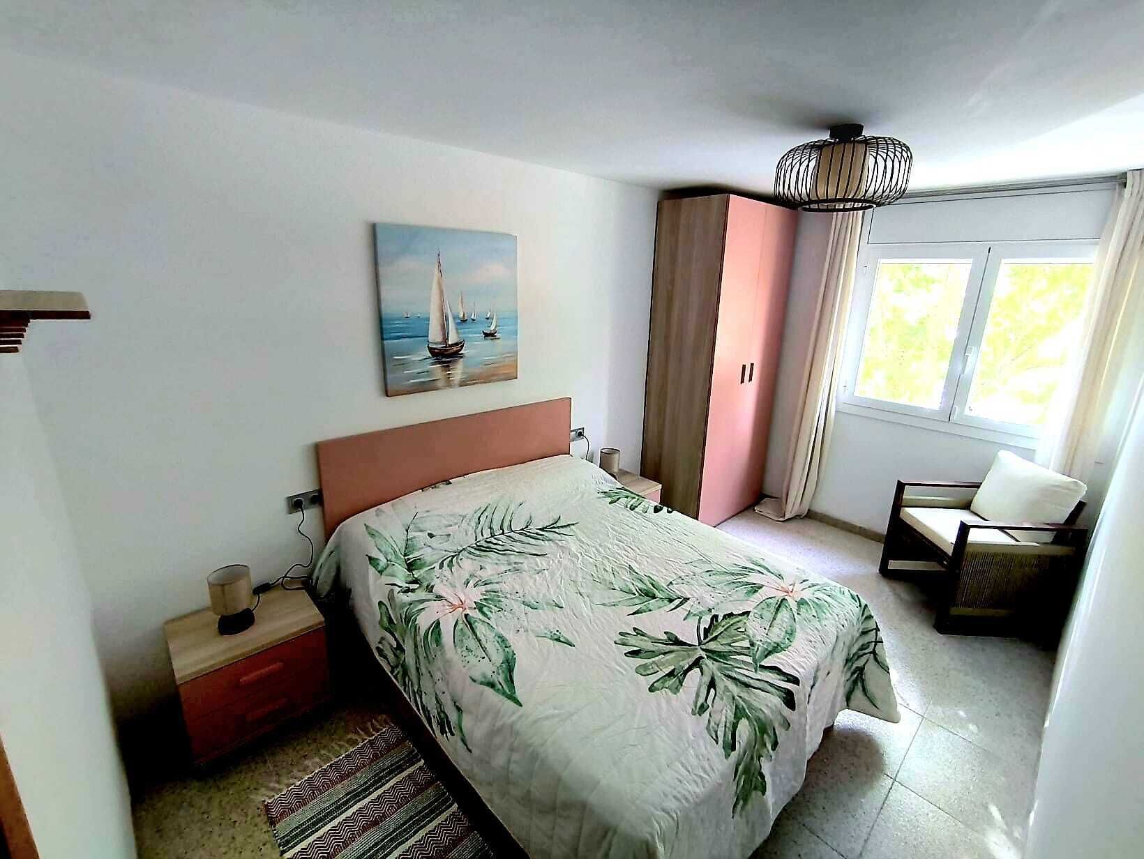 A bedroom with a bed, a nightstand, a wardrobe, a chair, a painting, and a window.