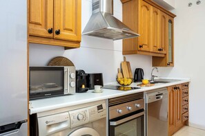 A compact kitchen with a built-in microwave, coffee maker, and oven. - A light-filled one-bedroom in Cuatro Caminos, where a private sixth-floor balcony looks out over open sky, a quiet place for morning coffee a short walk from the Bernabéu. (MADRID)