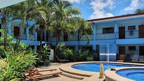 A pool area with a circular hot tub, lounge chairs, and a building with balconies. - Marina Loft #103, 1 Floor (Sardinal)