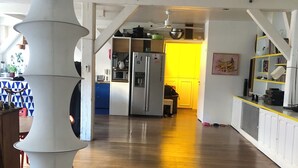 A spacious kitchen with a central island, a refrigerator, and a yellow wall in the background. - Spacious 170 m² Loft – 3 Bedrooms – Canal St-Martin – Fully Furnished & Designer (Paris)