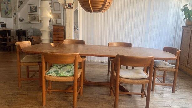 A dining area with a wooden table and chairs, a hanging light fixture, and a white wall with vertical blinds. - Spacious 170 m² Loft – 3 Bedrooms – Canal St-Martin – Fully Furnished & Designer (Paris)