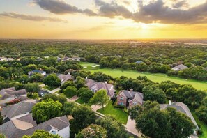 A residential area with houses, a golf course, and a sunset. - Luxury 5BR on Golf Course: Pool, Hot Tub, EV Charger (Round Rock)