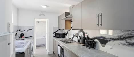 A modern kitchen with a gas stove, a microwave, and a coffee maker.