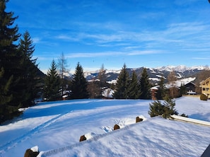 A snow-covered landscape with a clear sky, a wooden cabin, and a mountain range in the background. - Stay at the heart of the slopes in Megève! (Megève)