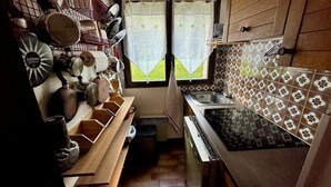 Uma cozinha compacta com fogão, pia e janela com cortinas.