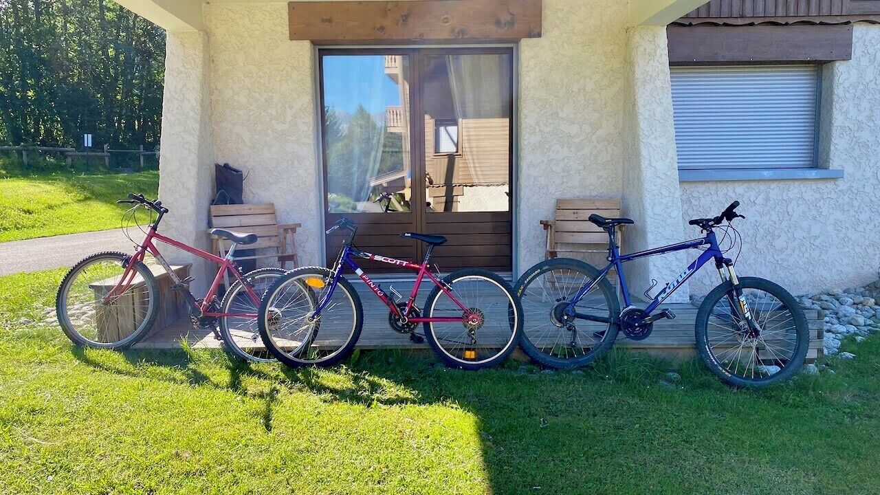 Un bâtiment doté d’un porche, d’un banc et d’un vélo garé à l’extérieur.