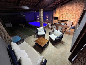 An outdoor patio with a pool, seating area, and a brick wall.