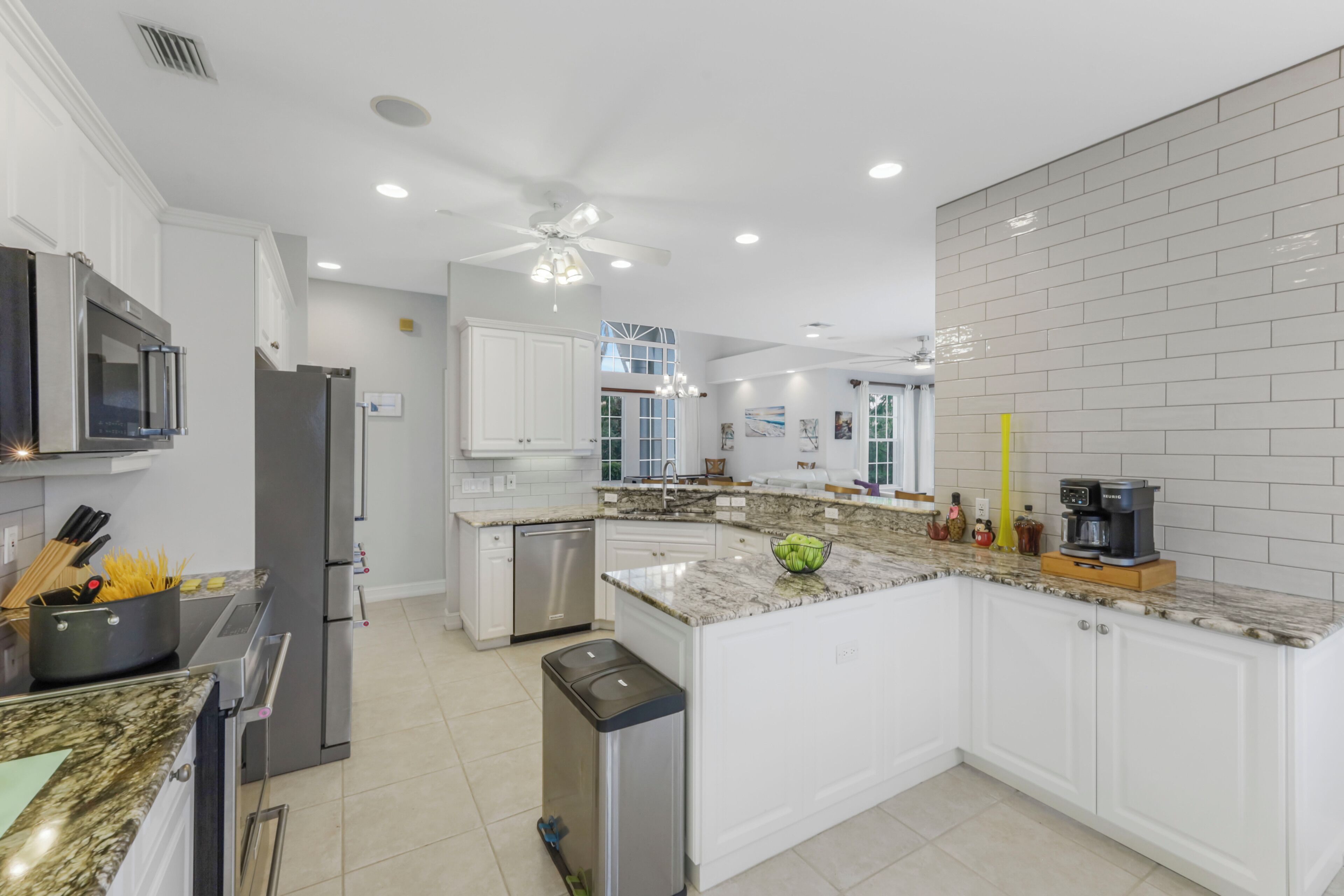 Una cocina moderna con muebles blancos, electrodomésticos de acero inoxidable y encimera de granito.