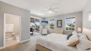 A bedroom with a bed, a chair, a ceiling fan, and a view of the outdoors. - Waterfront Home | Pool, Kayaks, Air Hockey & Foosball (Marco Island)