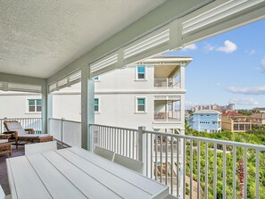 Un balcon avec des balustrades blanches, des meubles en osier et une vue sur les immeubles voisins.