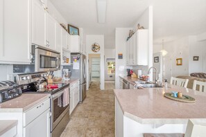Una cucina moderna con elettrodomestici in acciaio inossidabile, mobili bianchi e un'isola centrale.