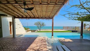 Un área de piscina con vistas al mar, un porche cubierto y un camino de ladrillo.