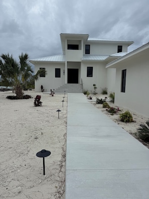 A modern two-story house with a concrete pathway leading to the entrance.