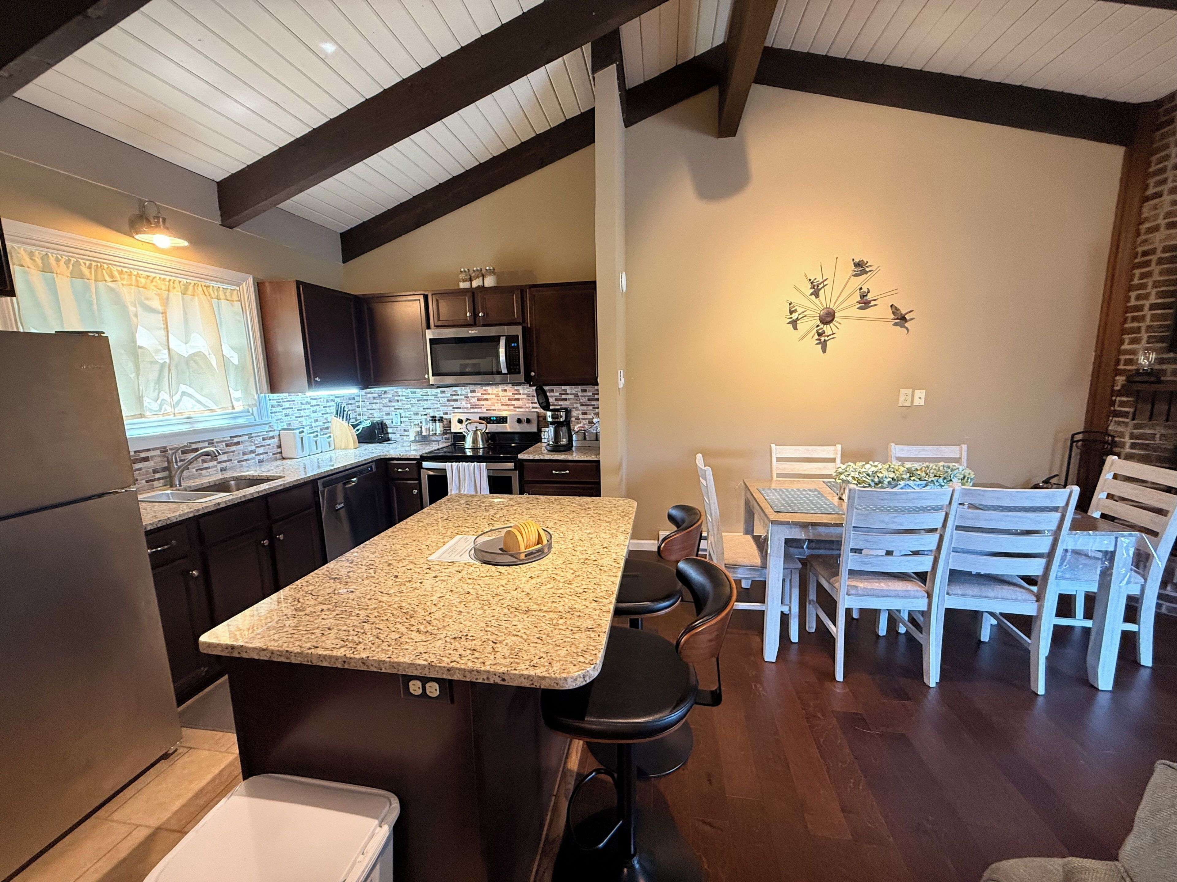 A kitchen with granite countertops, dark cabinetry, and a central island.
