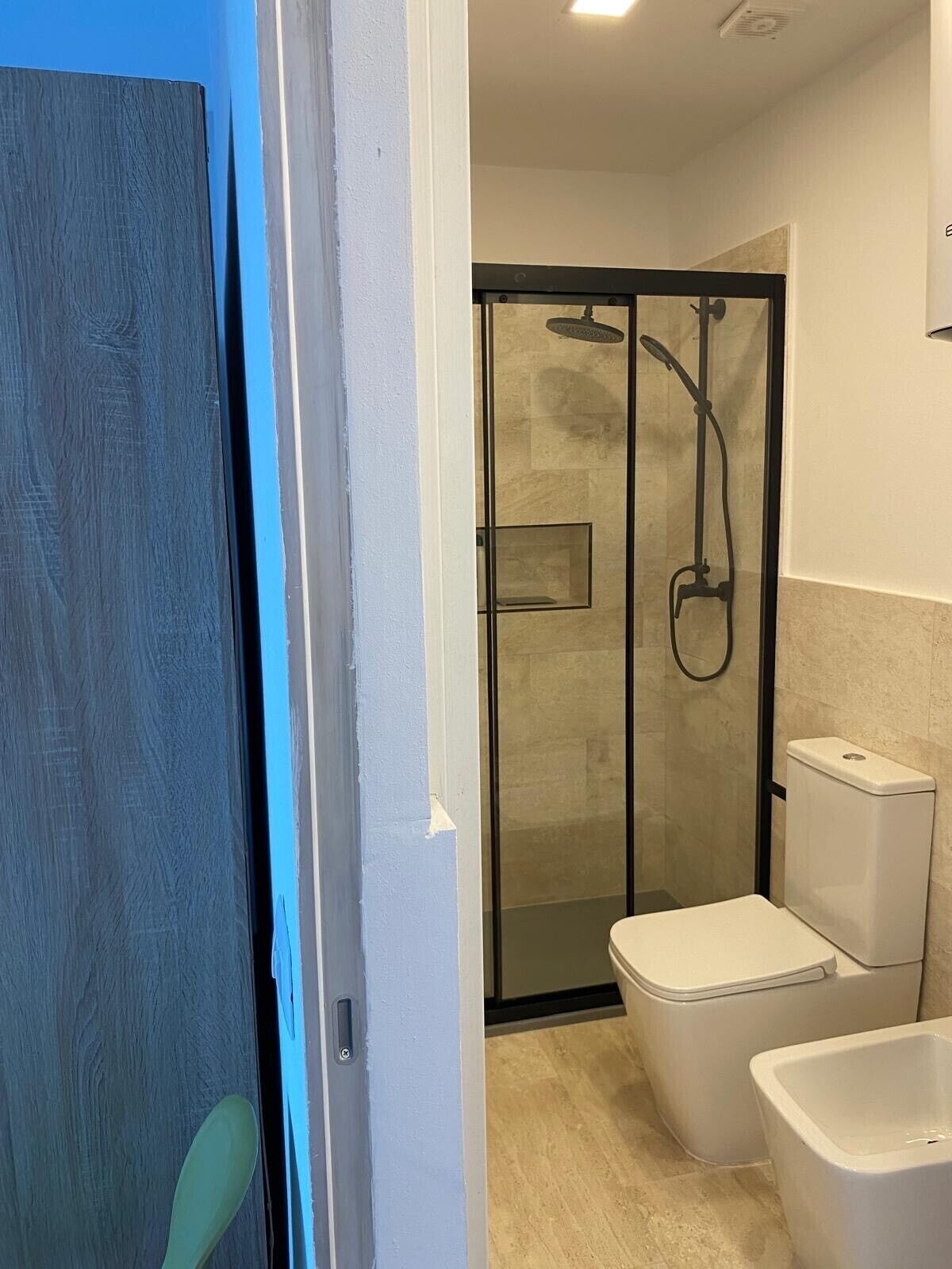 A bathroom with a glass shower enclosure, a toilet, and a bidet.