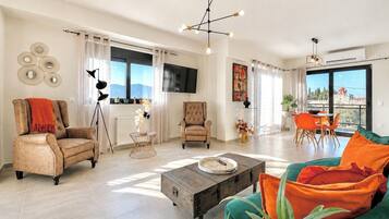 A spacious living room with a sofa, chairs, a coffee table, and a dining area with a view.