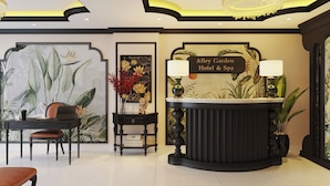 A reception desk with a sign reading 'Alley Garden Hotel & Spa,' a chandelier, and a wall with tropical plant artwork. - Alley Garden Hotel & Spa (Hanoi)
