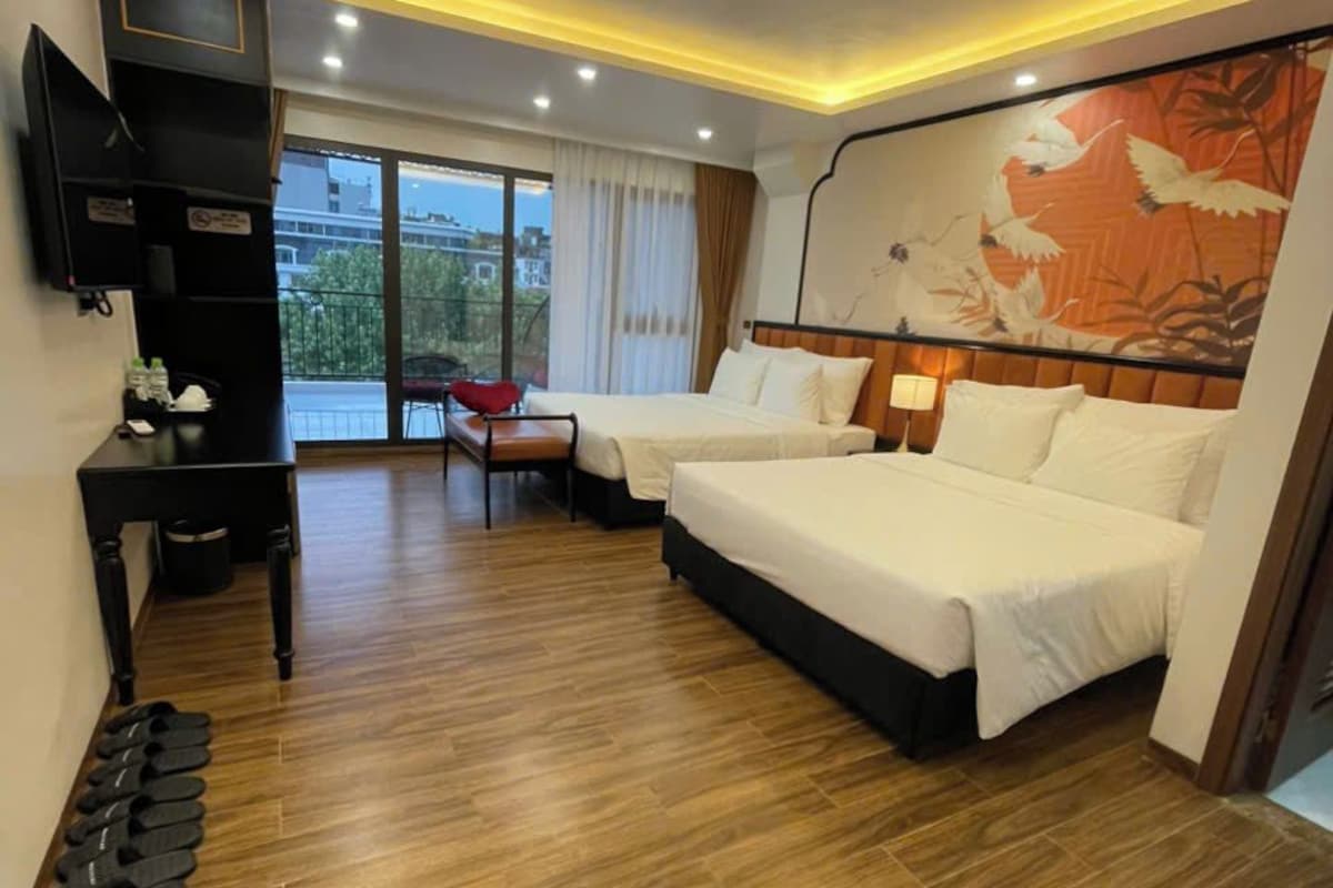 A hotel room with two beds, a desk, a TV, and a large window with a view.