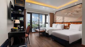 Habitación de hotel con balcón, dos camas, escritorio con lámpara y un mural grande en la pared.