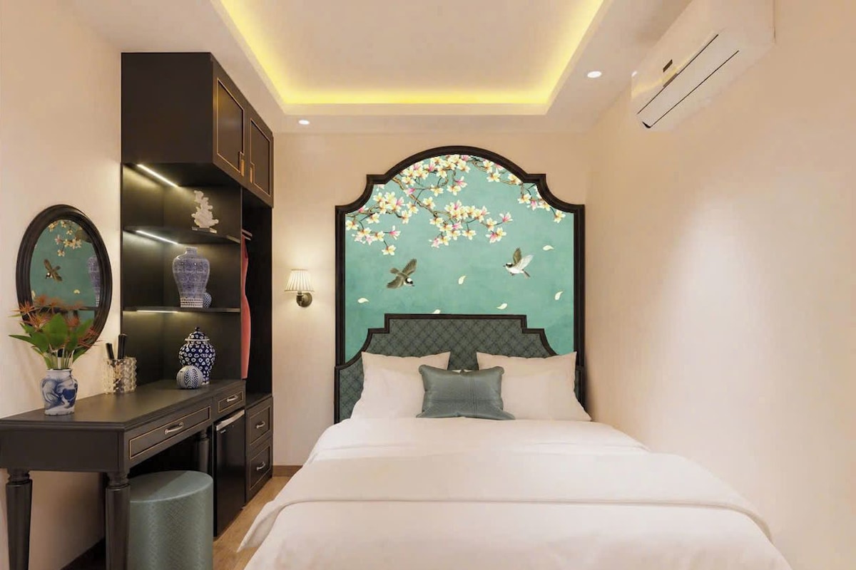 A hotel room with a bed, a desk, and a vanity.