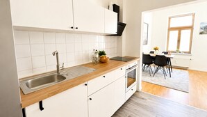 A modern kitchen with white cabinets, a wooden countertop, a stainless steel sink, and a built-in oven. - N&N: Apartment - in the heart of the Old Town (Wismar)