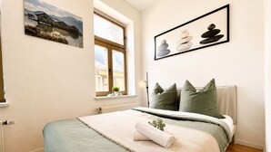 A bedroom with a bed, pillows, a window, and a painting on the wall. - N&N: Apartment - in the heart of the Old Town (Wismar)
