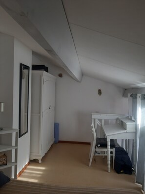 Een kamer met een witte kast, bureau en bed.