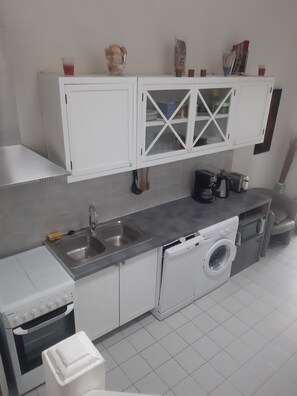 A kitchen with white cabinets, a stainless steel sink, a built-in oven, and a dishwasher. - Vacation in Portiragne-Plage (Portiragnes)