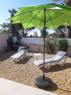 A patio with two lounge chairs and a green umbrella. - Vacation in Portiragne-Plage (Portiragnes)