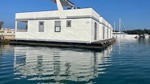 A stationary houseboat with a flat roof, windows, and a small deck area. - Modern Houseboat for 6 People (Novigrad)