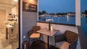 A dining area with a view of the water, a sign for Sea Lodge, and a table with chairs. - Modern Houseboat for 6 People (Novigrad)
