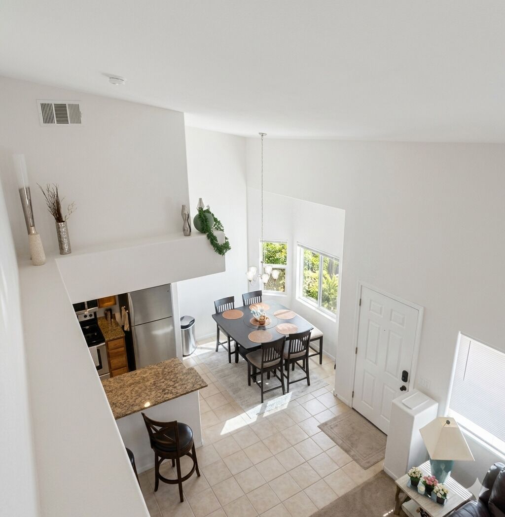 A modern kitchen with a dining area, a small bar, and a view of greenery outside.