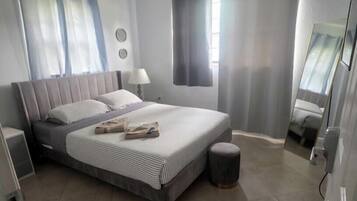 Une chambre à coucher avec un lit, des rideaux, un miroir et un ventilateur de plafond.