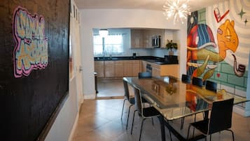 Une cuisine moderne avec des meubles en bois, une table à manger en verre et une fresque murale.