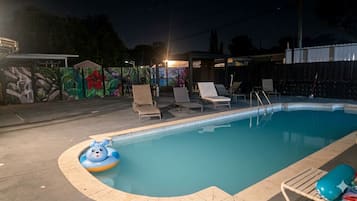 Une piscine avec des chaises longues et une fresque murale.