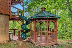 A wooden gazebo with a spiral slide attached to a wooden deck. - 🏔️ Mountain Views + Hot Tub | Loaded Game Room | Sleeps 10 (Pigeon Forge)