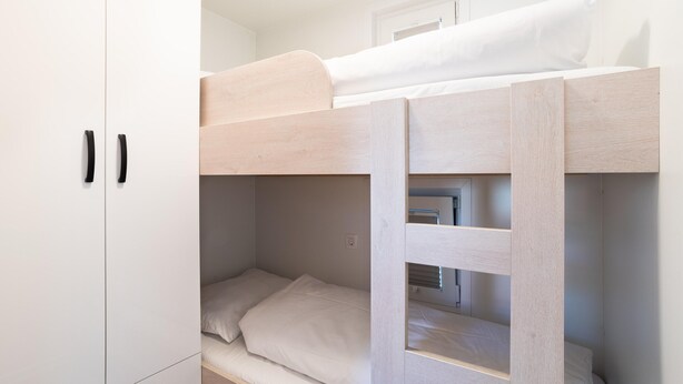 A bunk bed with a white mattress and a wooden frame, a white wardrobe with two doors, and a window with blinds. - Dream Houseboat by the sea With Terrace (Piran)