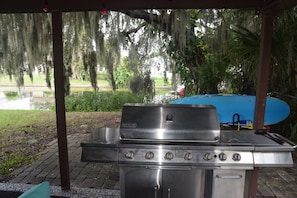 Un barbecue extérieur avec vue sur un étang et des arbres.