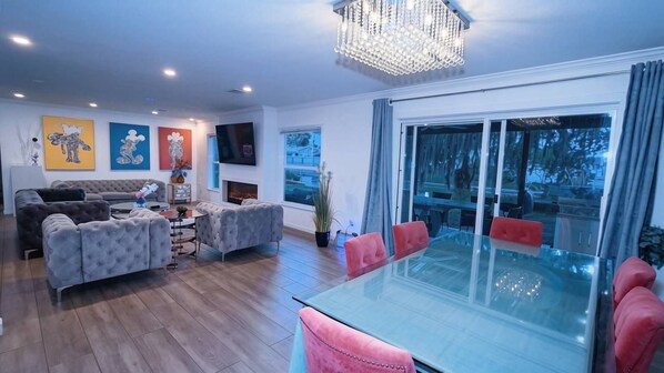 Uma sala de estar moderna com uma mesa de jantar de vidro, sofás e um candelabro.