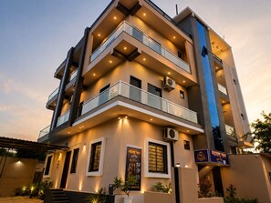 A multi-story building with balconies, air conditioning units, and a signboard.