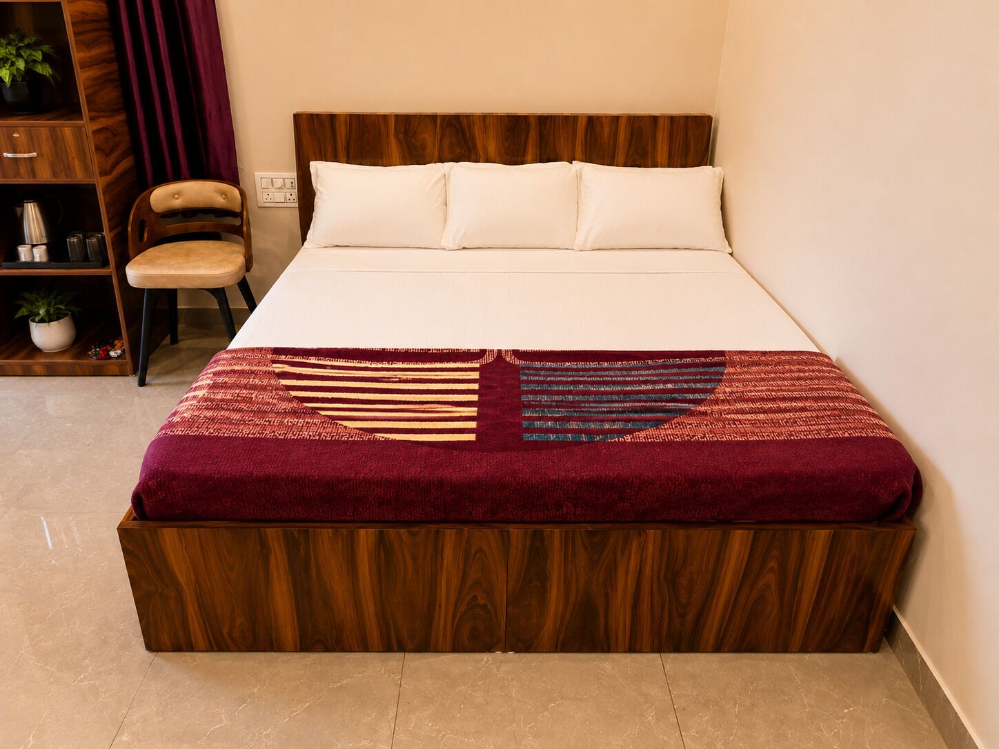Una cama con cabecera de madera, una silla color beige y una estantería con una planta.